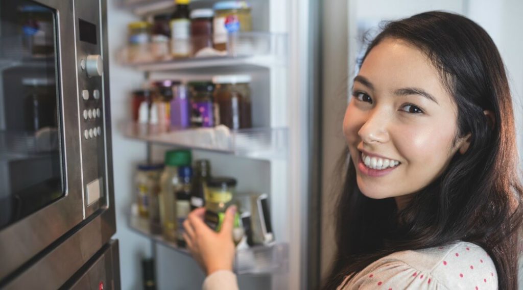 woman checking fridge storage space